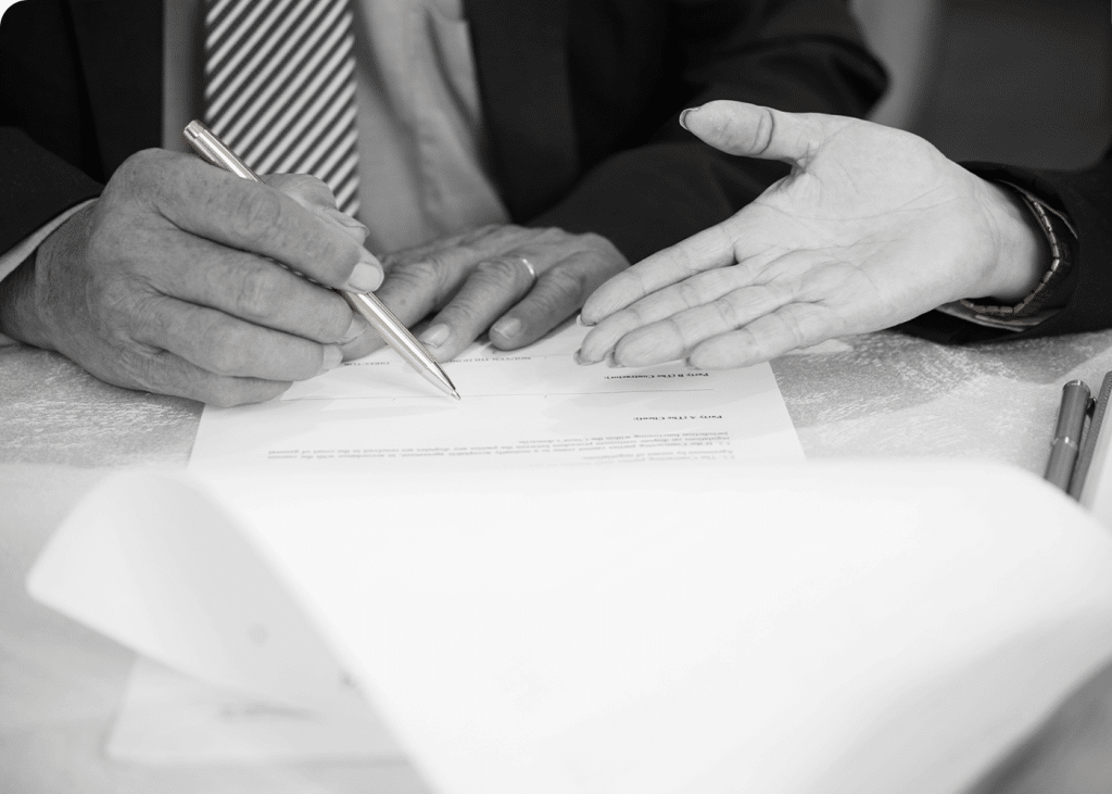 Deux personnes en train de signer un document avec un stylo doré.
