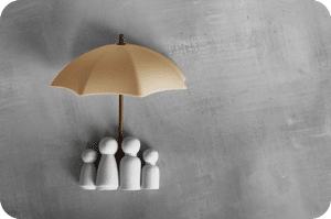 Figurines sous un parapluie beige, représentant la protection des assurances collectives.