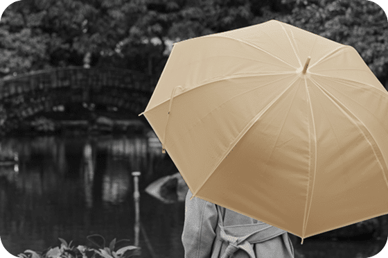 Personne tenant un parapluie beige, représentant la protection et la sécurité.