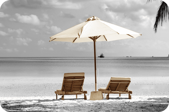 Deux chaises longues sous un parasol sur une plage tranquille avec vue sur la mer, représentant une retraite paisible.