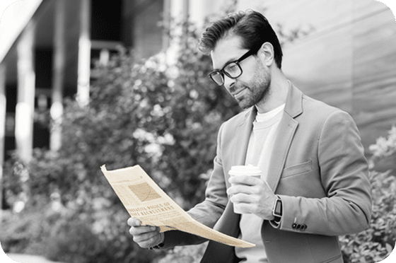 Un homme d'affaires lisant un journal en tenant une tasse de café.