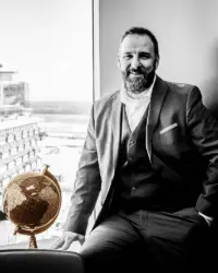 Denis Bourque, conseiller financier assis sur chaise avec globe or | Planico